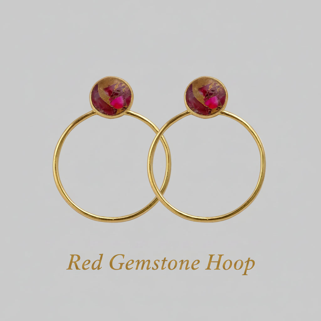 Gold hoop earrings with red gemstones on a white background